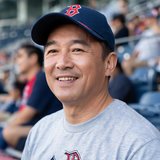 一位四十岁左右的男性球迷，戴着棒球帽，面带微笑