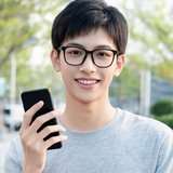 一位戴眼镜的年轻男性，面带自信笑容，手持手机